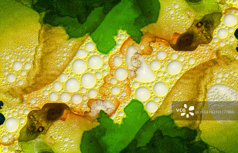 抽象背景，黄色和绿色墨水液体在画布上混合，带有浮雕气泡的纹理图片素材