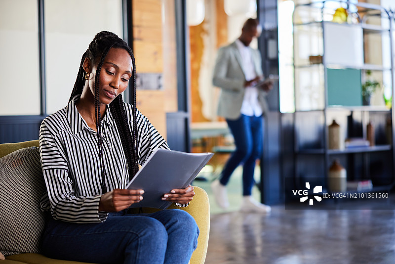 在办公室沙发上阅读文件的年轻女商人图片素材