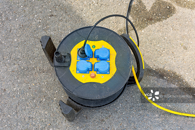 带蓝色插头和黄色电缆的黑色电缆盘图片素材