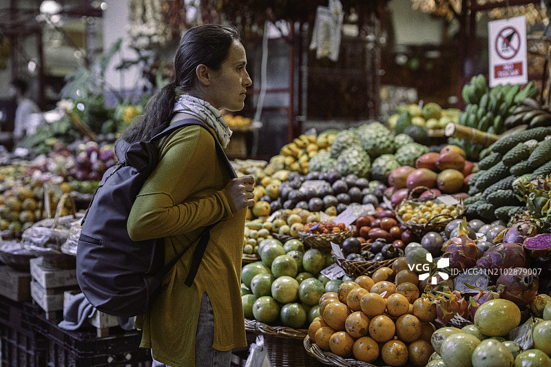 独特的单人旅行：在市场上购买热带水果图片素材