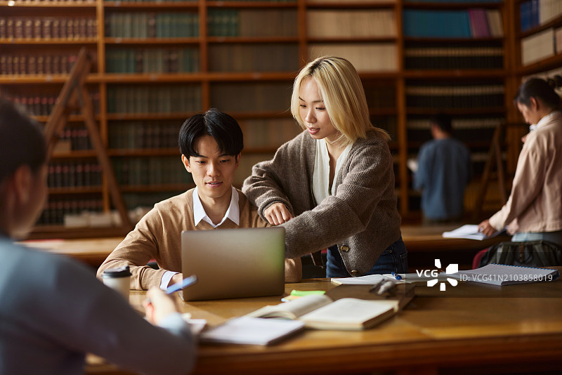 在图书馆用笔记本电脑学习的亚洲大学生情侣图片素材