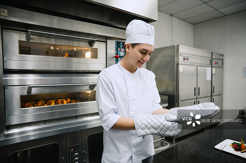 亚洲厨师在商用厨房准备戴手套图片素材