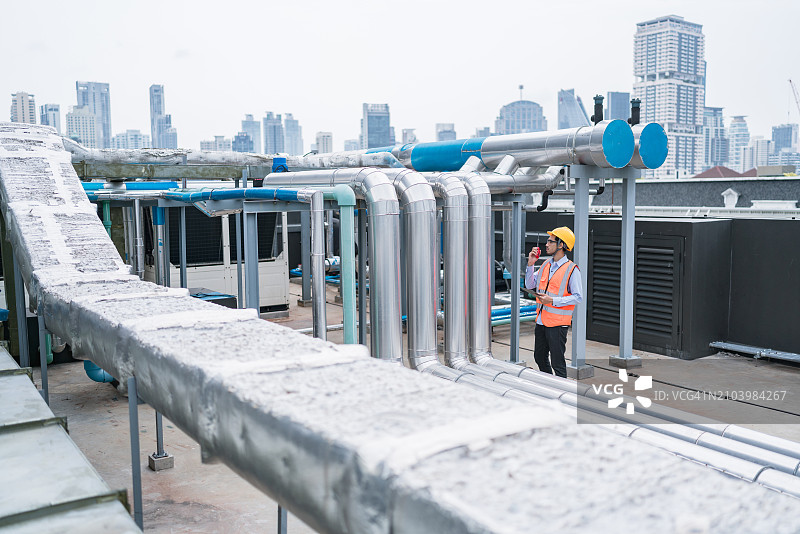 工程师在城市地区监督屋顶工业管道图片素材