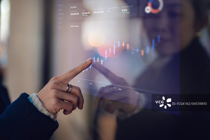 年轻亚洲女商人分析互动屏幕上的财务数据特写镜头图片素材