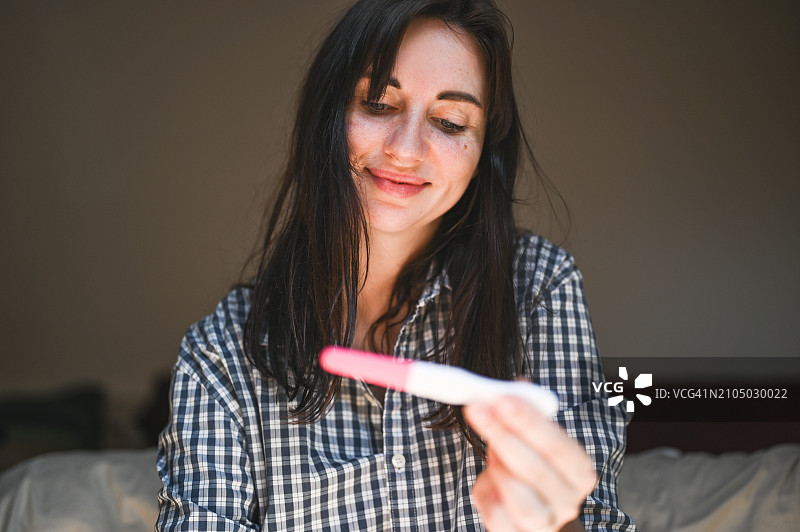 微笑的女人看着验孕棒图片素材
