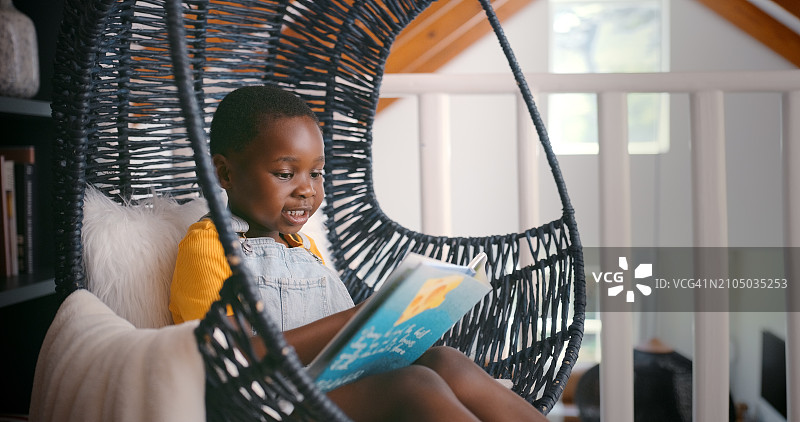 女孩在卧室的椅子上阅读儿童书籍图片素材