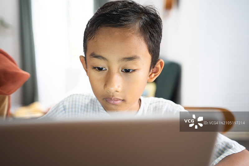 亚洲年轻男孩在家与母亲一起使用笔记本电脑学习图片素材