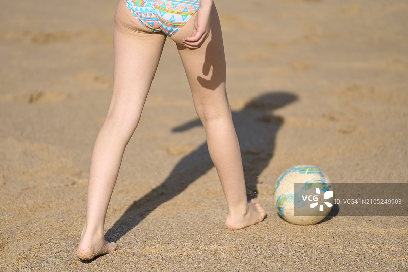 阳光明媚的日子里，比基尼女孩在沙滩上行走，后视图图片素材