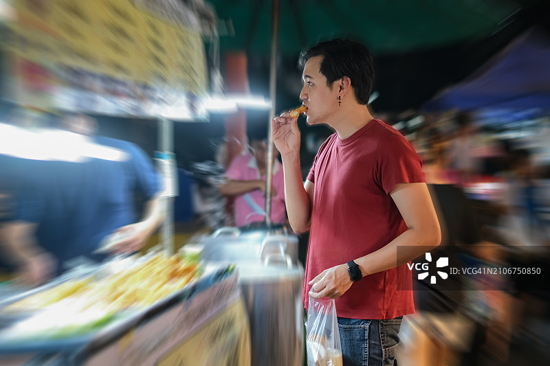 年轻亚洲男人街头享用豆浆油条图片素材