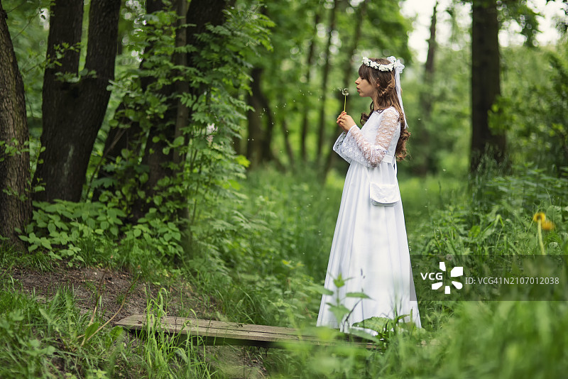 小女孩穿着白色连衣裙，拿着蒲公英图片素材