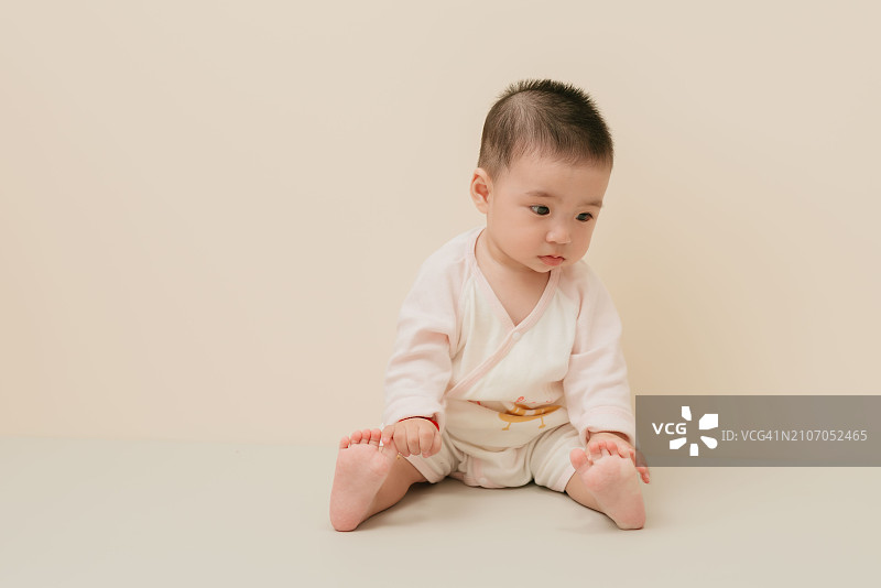 穿着休闲服在地上玩耍的华裔婴儿图片素材