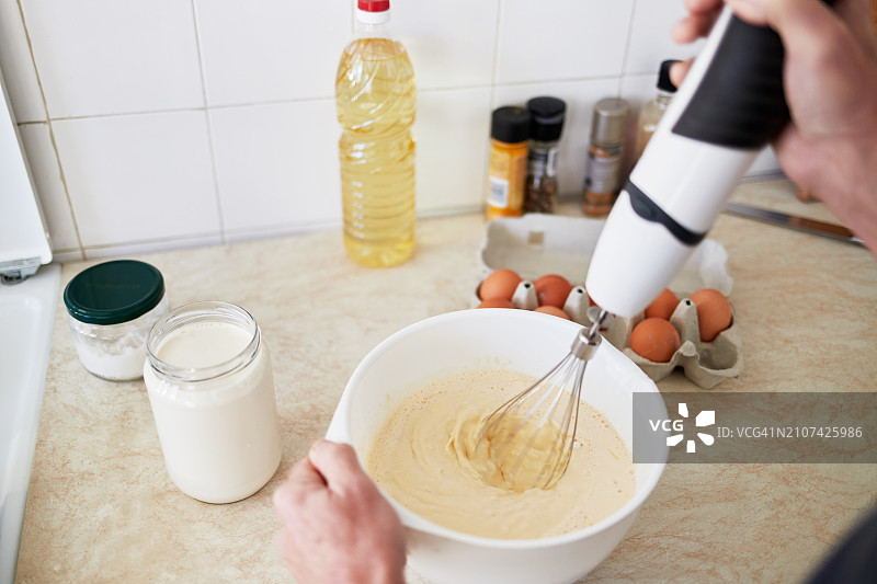 男人用搅拌机混合自制薄煎饼面团，家庭烹饪概念图片素材