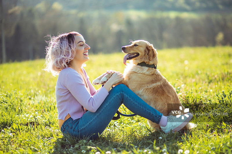 粉色头发的女人和她的金毛猎犬在户外玩耍图片素材