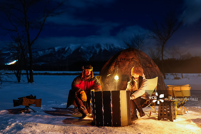 情侣在冬季营地篝火旁放松图片素材