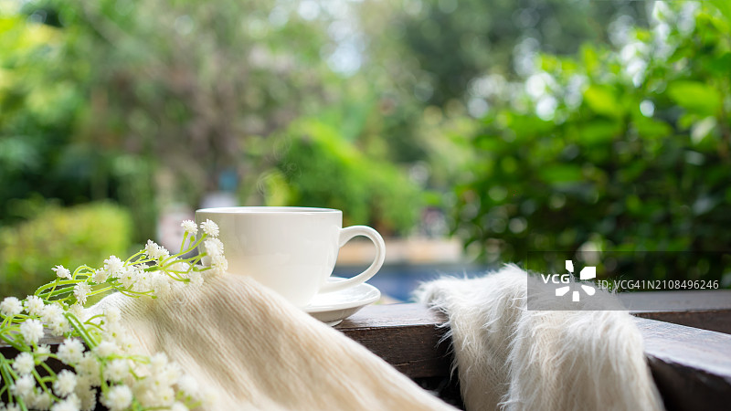 热咖啡与耳机木桌泳池绿色自然背景图片素材
