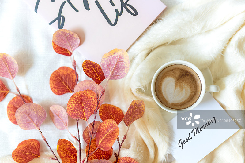 在记事本上书写文本：早上好。注意身体健康。咖啡杯，搭配红叶，放松和休息一下，顶视图。生活方式健康概念图片素材