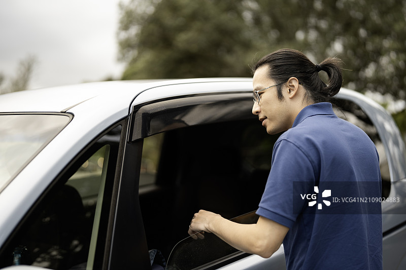 亚洲男人扒着车窗向车内看图片素材