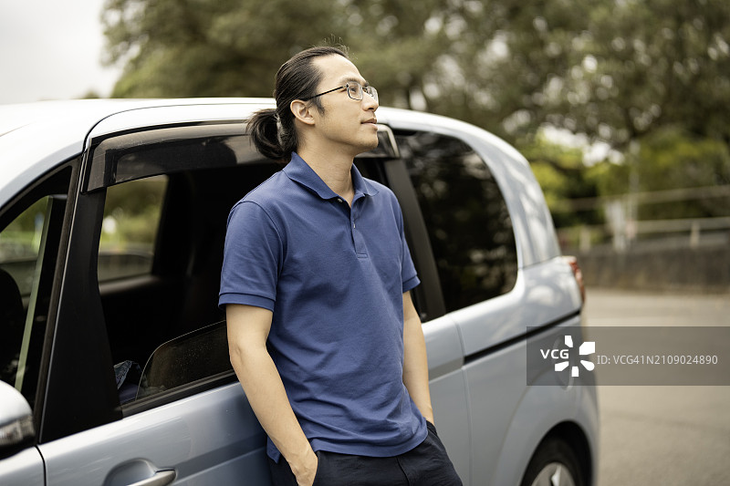 亚洲男人靠在车门上，眺望远方图片素材
