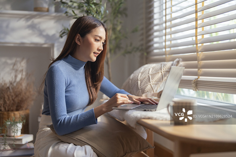 微笑的亚洲自由职业女性居家办公图片素材