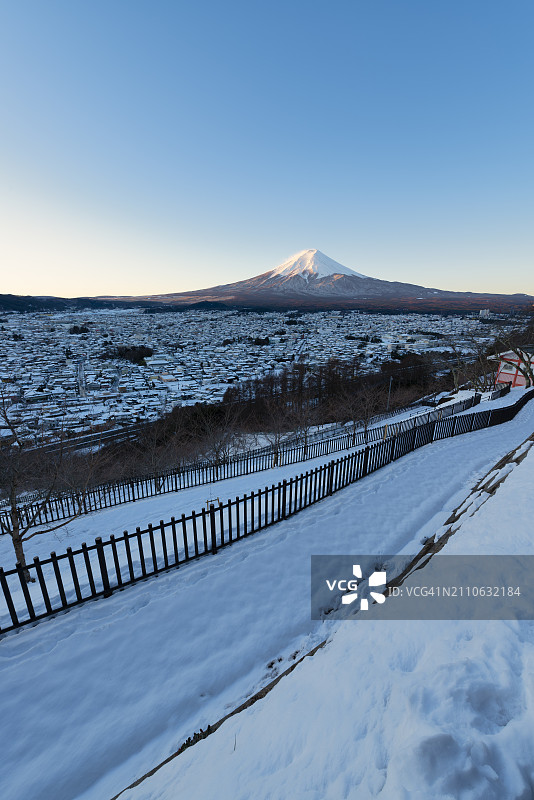 冬季早晨白雪覆盖的富士吉田市上空的富士山图片素材