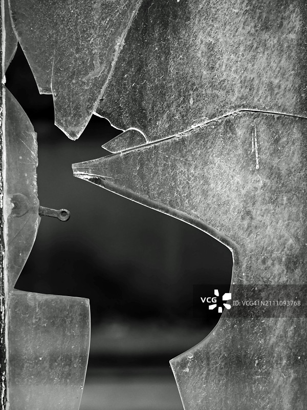 破碎窗户的特写。法国巴黎一栋废弃房屋的细节。户外拍摄的黑白照片：日光。图片素材