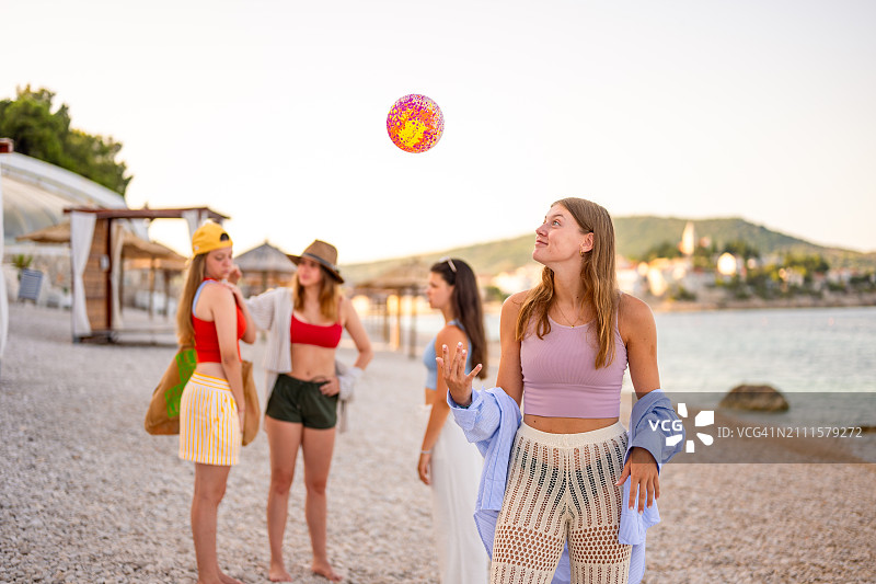 在海滩上和朋友一起玩球的年轻女孩图片素材