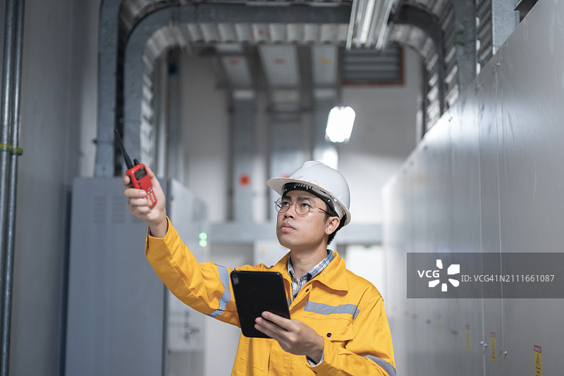 电工工程师和使用平板电脑检查配电室电气设备图片素材
