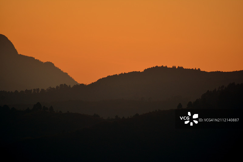 橙色天空映衬下群山剪影的美景图片素材