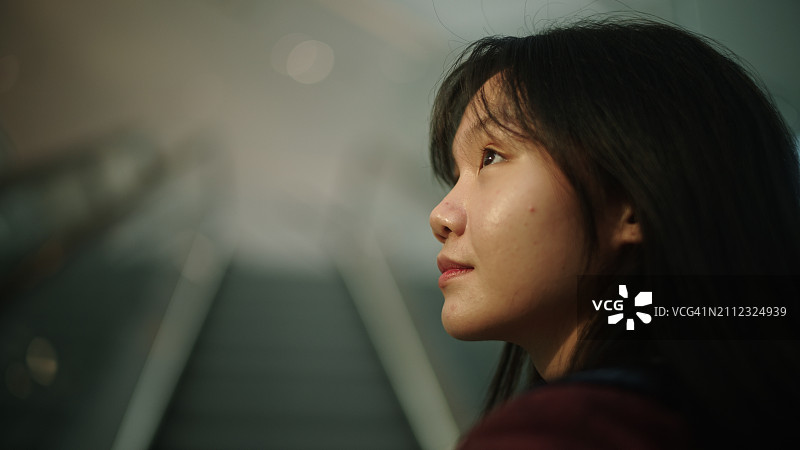 站在向上移动的自动扶梯上的少女图片素材