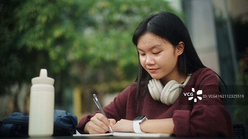 亚洲女孩在书上做笔记图片素材