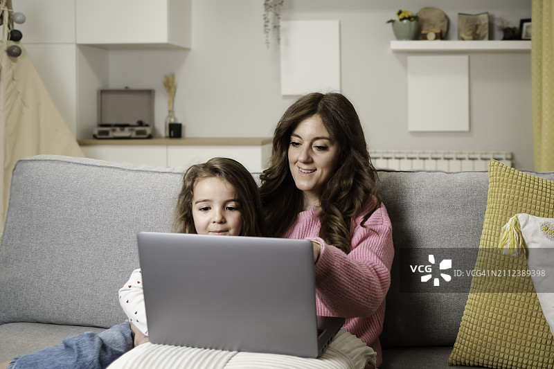 母亲和女儿在家中使用笔记本电脑图片素材