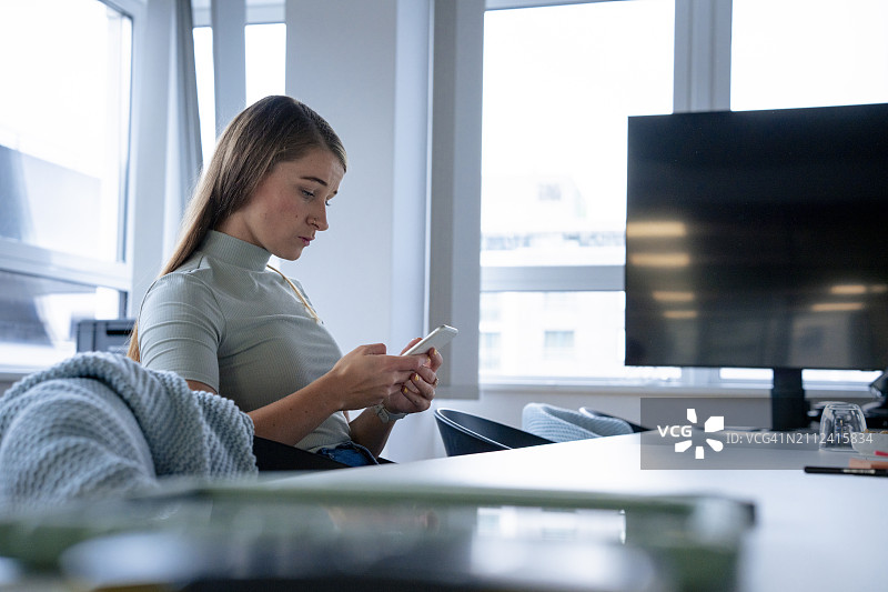 女商人坐在办公室里使用智能手机图片素材