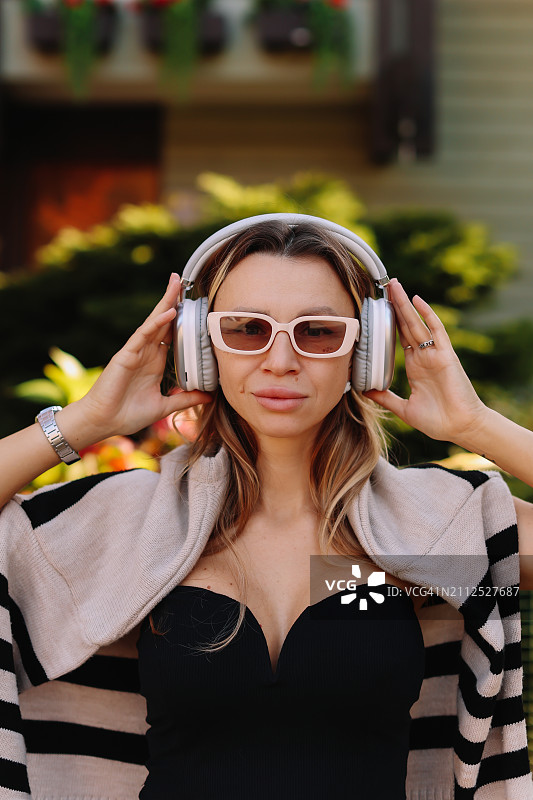 戴着太阳镜和无线耳机的女人在秋天的大自然中边走边听音乐图片素材