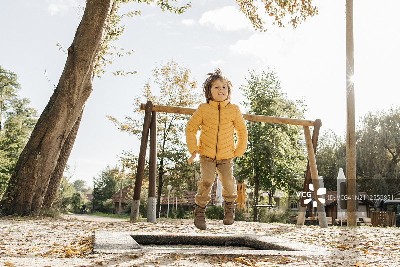 小男孩在操场上跳蹦床图片素材