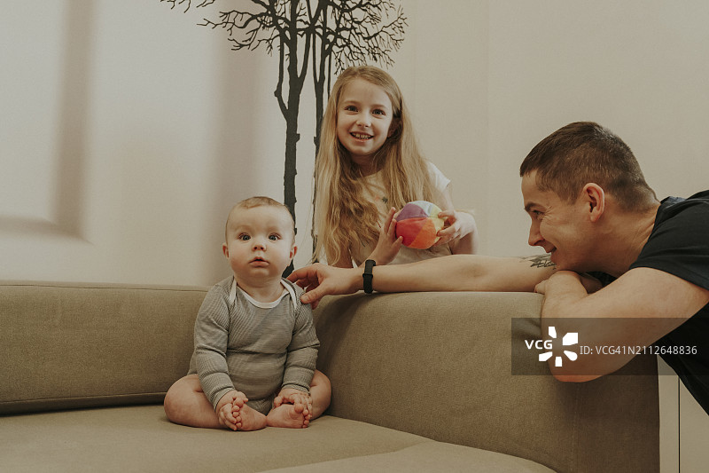 幼儿在家中坐在沙发上，靠近家人图片素材
