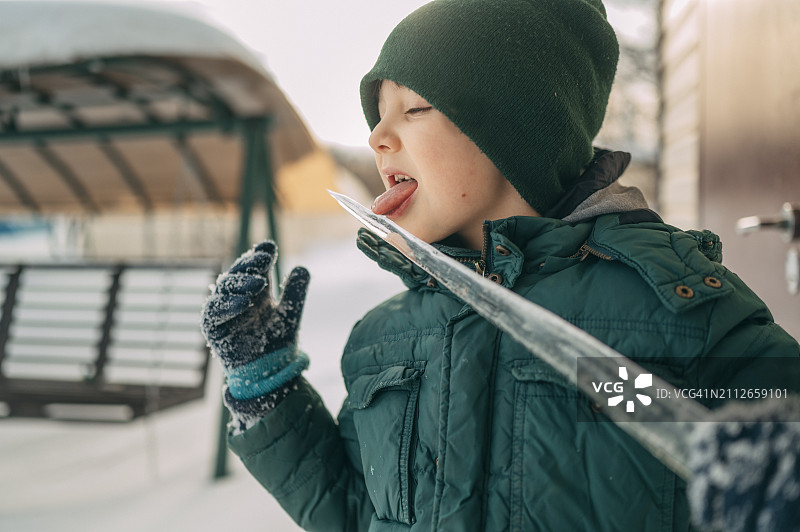 调皮的男孩舔着冬天的冰柱图片素材