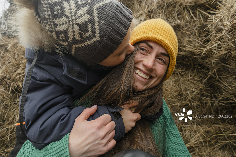 在农场干草堆旁拥抱母亲的男孩图片素材