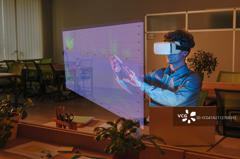 在办公室使用虚拟现实模拟器与图形界面交互的商务男人图片素材