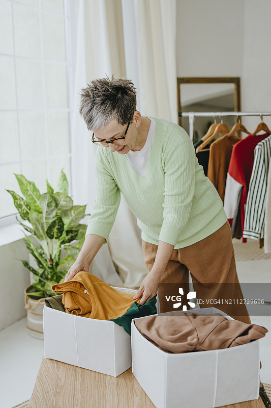 中年妇女在家整理旧衣服准备捐赠图片素材