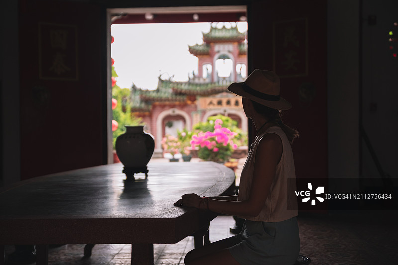 在中国寺庙里坐在桌旁戴帽子的女子剪影图片素材