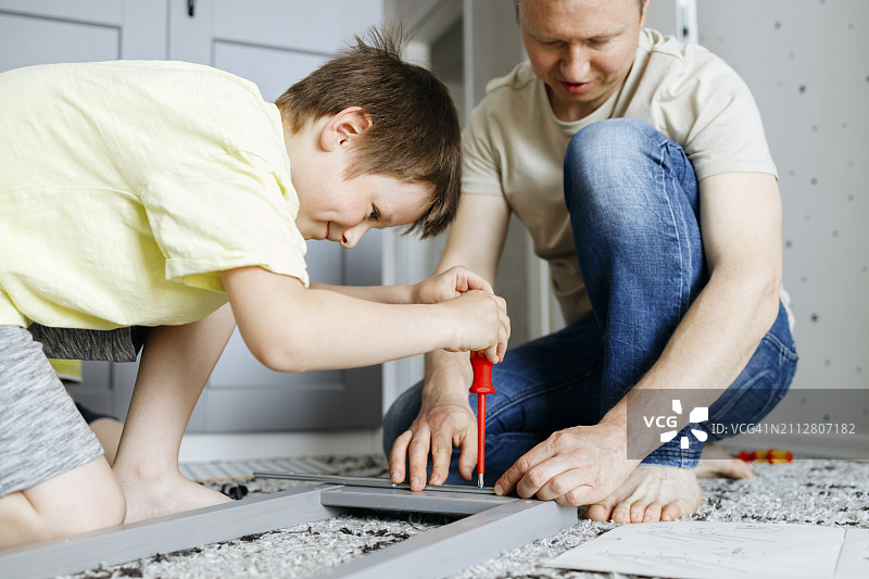 儿子和父亲在家组装床头柜图片素材