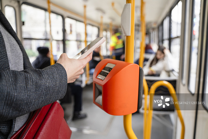 女人在有轨电车上用智能手机购票图片素材