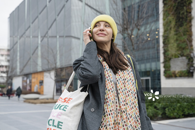 笑容满面的女人在城市里用智能手机通话图片素材