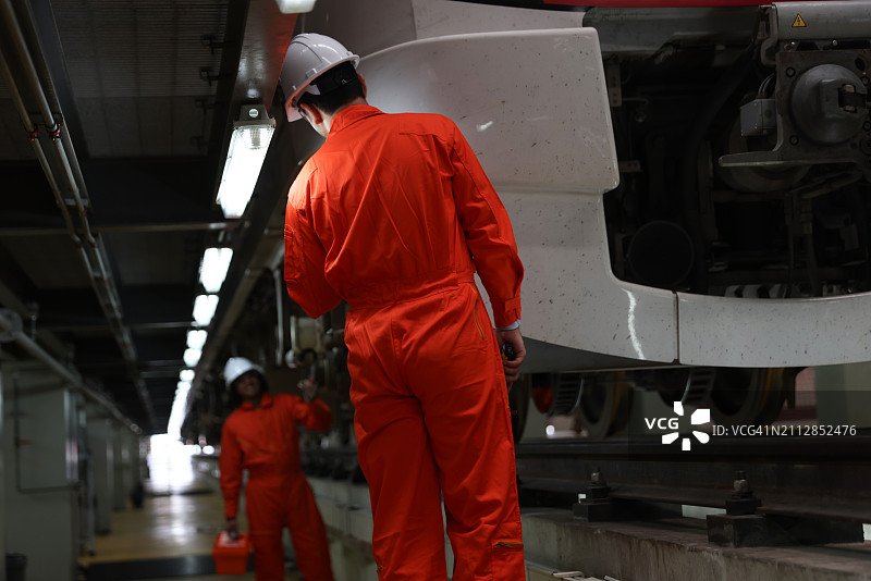 两名尽职的火车工程师检查电力火车部件图片素材