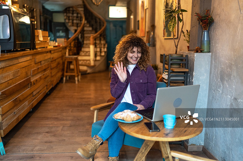 在咖啡馆室内用笔记本电脑进行视频通话的漂亮女人图片素材