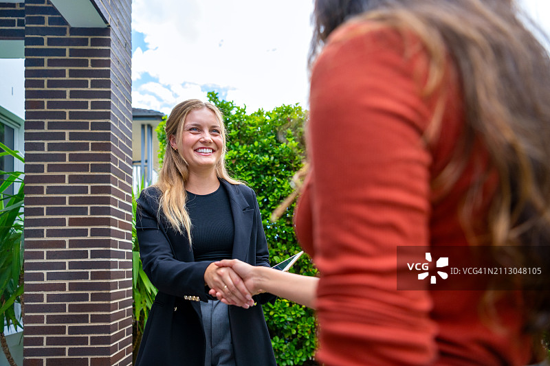 房地产经纪人向一位女士展示新房，可以看到部分前花园图片素材