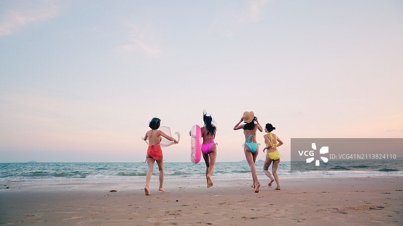 亚洲女人和朋友在海滩上快乐奔跑，享受暑假图片素材