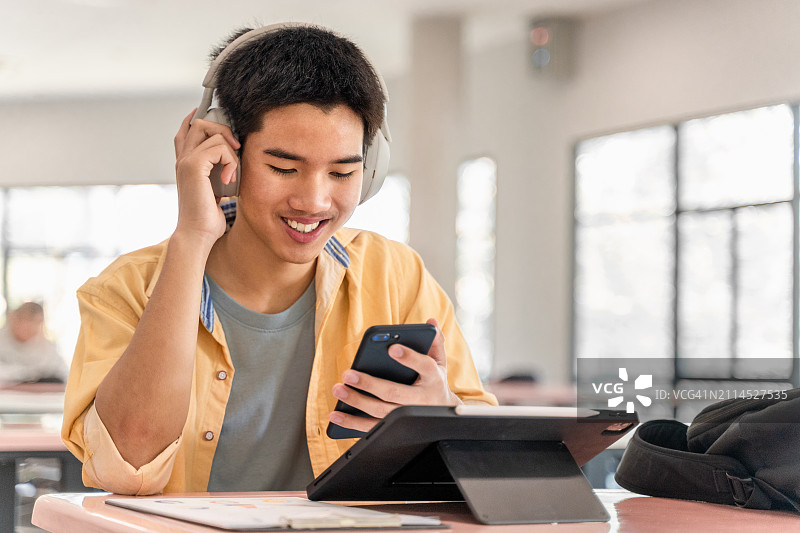 快乐的Z世代在学校学习时，通过电脑平板和手机设备进行在线投资图片素材