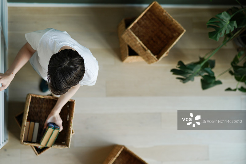 青少年男生整理家庭图书馆，放入柳条箱图片素材