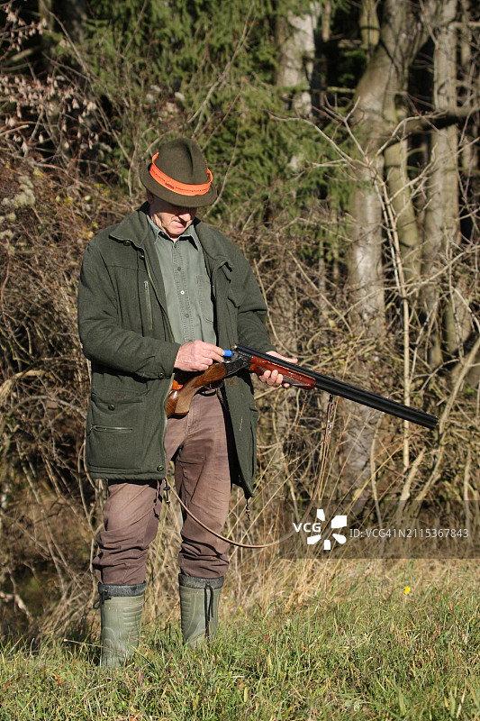 猎人在奥地利狩猎棕兔时将猎枪弹装入步枪图片素材